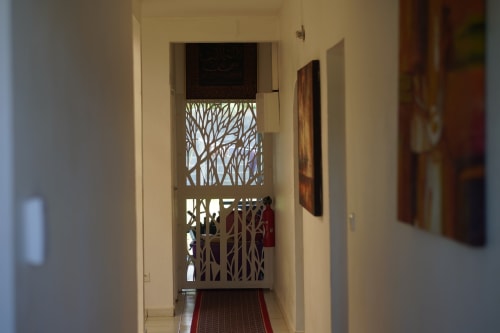 Couloir du gîte Kaz Kafe à Mamoudzou avec portes décoratives en bois et œuvres d'art