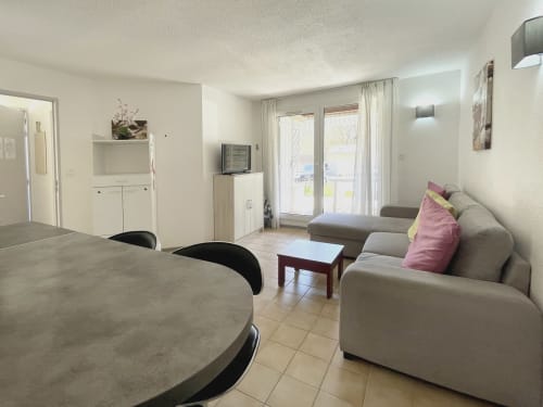 Appartement ouvert au Vallon des Sources à Digne-les-Bains avec canapé beige, table à manger, kitchenette et portes vitrées