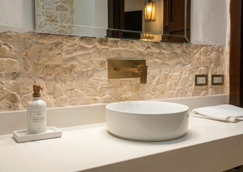 Baño de lujo en Villa Merida Boutique Hotel con lavabo blanco moderno, backsplash de travertino y accesorios elegantes
