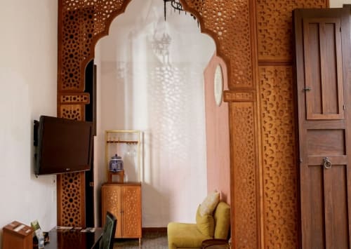 Habitación boutique Villa Merida con biombos de madera ornamentada, sillón amarillo, televisor y arquitectura tradicional marroquí