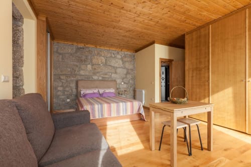 Aconchegante estúdio de madeira na Casa da Lagiela com cama listrada, parede de pedra e vista para a montanha em Fafe, Portugal