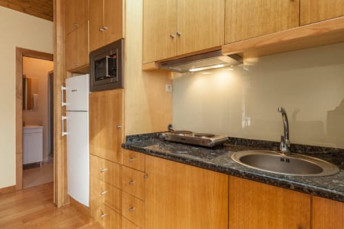 Cozinha moderna com armários em madeira, bancada de granito e pia em aço inoxidável na Casa da Lagiela
