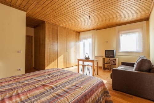 Espaçoso estúdio na Casa da Lagiela em Fafe com teto de madeira, cama, sofá, TV e vista para a montanha