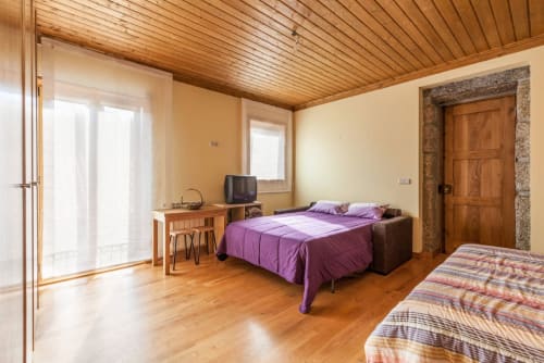 Espaçoso estúdio na Casa da Lagiela em Fafe com cama roxa, piso de madeira, vista para as montanhas e amenidades modernas