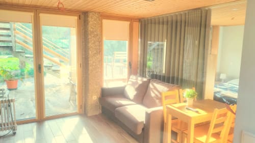 Sala de estar clara com sofá cinza, mesa de jantar, cadeiras de madeira e portas para o pátio com vista para a piscina