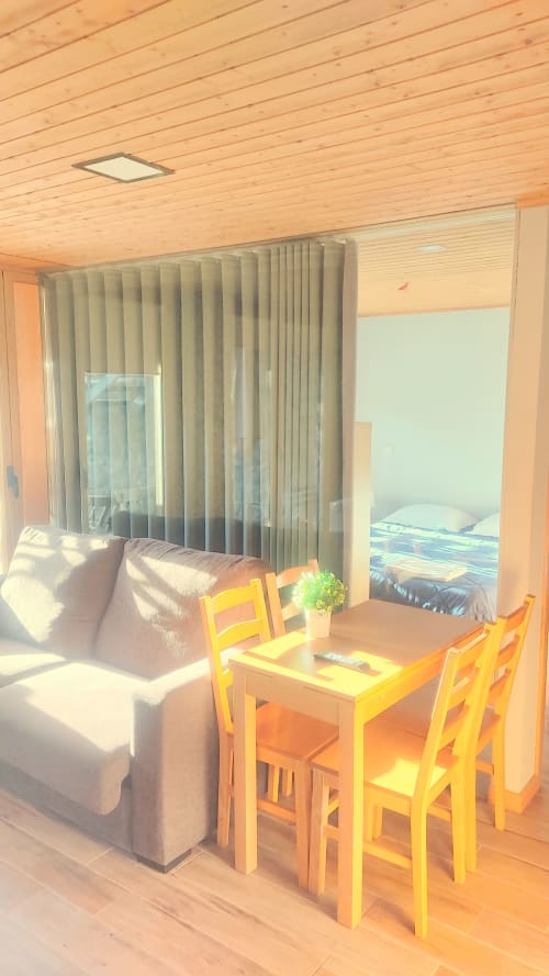 Estúdio luminoso em Casa da Lagiela com mesa de jantar, cadeiras amarelas, sofá e vista para a piscina