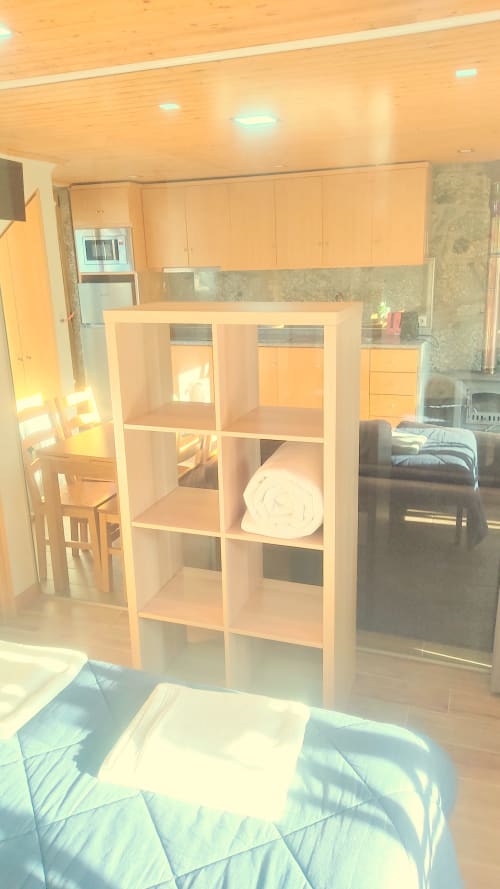 Interior luminoso do apartamento Casa da Lagiela em Fafe com prateleiras de madeira, área de cozinha e móveis confortáveis