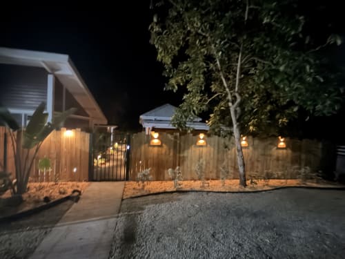 Filao Cottage nighttime exterior view in Sainte-Rose, Guadeloupe, with illuminated wooden fence, gated entrance, and tropical