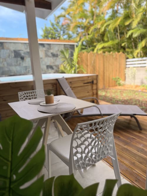 Private patio at Filao Cottage with modern white chairs, dining table, and lush garden views in Sainte-Rose, Guadeloupe