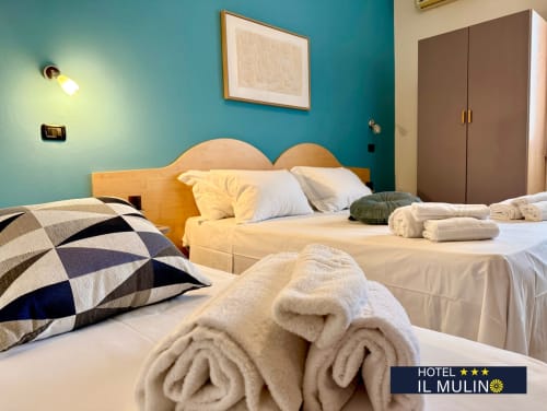 Camera tripla Hotel Il Mulino a Villalunga con pareti turchesi, letto in legno e asciugamani bianchi