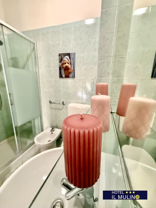 Bagno con doccia in vetro, toilet, bidet e candele decorative rosse presso l'Hotel Il Mulino, Villalunga