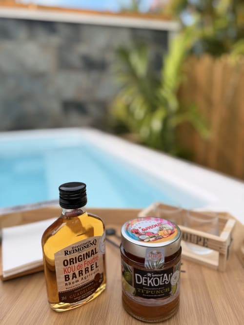 Rum bottle and Dekolaj spread on wooden tray by Filao Cottage private pool in Guadeloupe