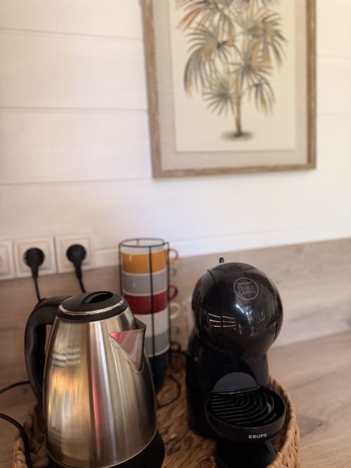 Cottage kitchenette at Filao in Sainte-Rose with electric kettle, Nescafé Dolce Gusto machine, and colorful mug on wooden