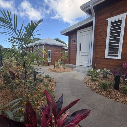 Cottage Filao Grande Anse à Sainte-Rose : bungalow en bois entouré de palmiers et jardins tropicaux