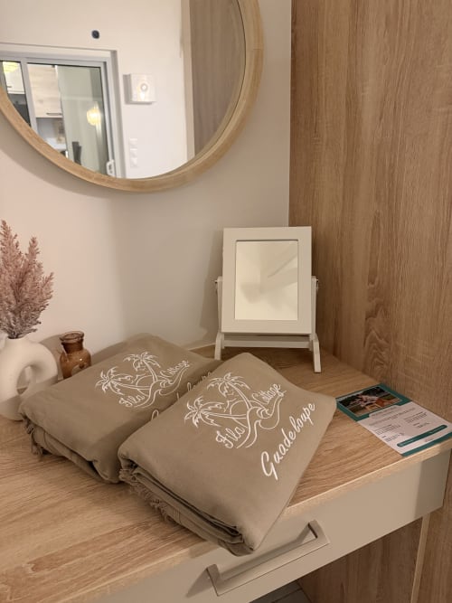 Coastal cottage bedroom at Filao Cottage with beige bedding, wooden vanity mirror, and pampas grass decor