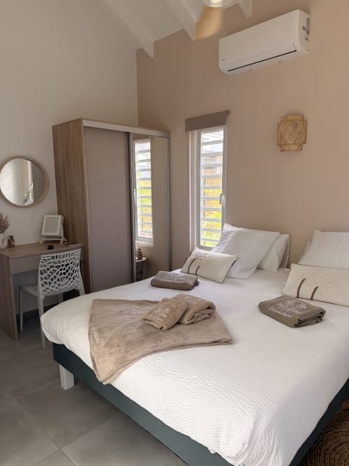 Modern bedroom at Filao Cottage in Sainte-Rose with two beds, wardrobe, desk, and air conditioning