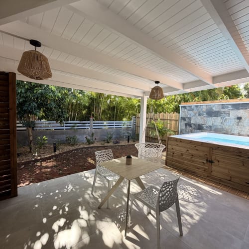 Filao Cottage Grande Anse patio with dining table, woven pendant lights, and pool in Sainte-Rose, Guadeloupe