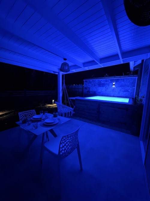 Filao Cottage Grande Anse cottage patio at night with blue lighting, dining table, and illuminated pool