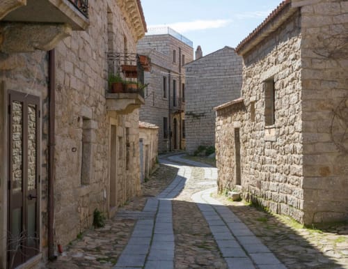 Stretto vicolo lastricato circondato da storici edifici in pietra a Valledoria, Italia presso A Mare Case Vacanze