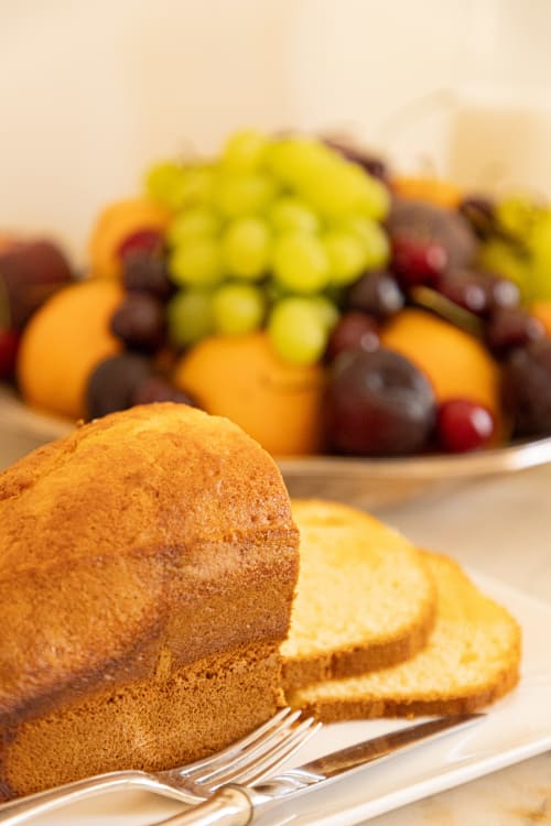Torta di spugna dorata con porzioni affettate e frutta fresca a Villa Ceci, Andria