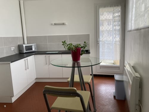 Cuisine moderne et coin repas dans l'appartement de Châtillon-sur-Seine avec cuisine équipée, table ronde en verre et accès à