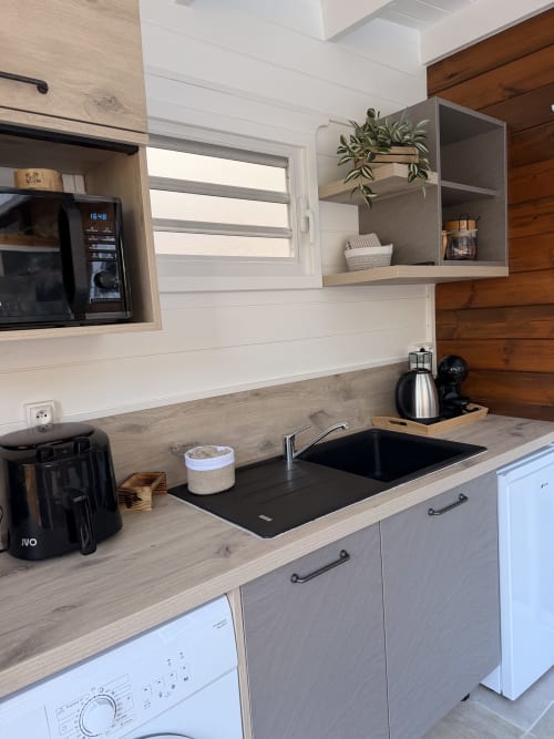 Modern kitchenette at Filao Cottage with black sink, wooden counters, white cabinetry, and stainless steel appliances