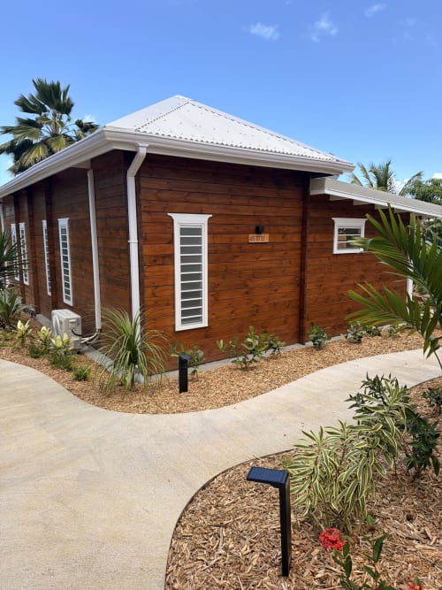 Bungalow en bois Filao Cottage à Sainte-Rose avec finitions blanches, toiture pentue et aménagement tropical