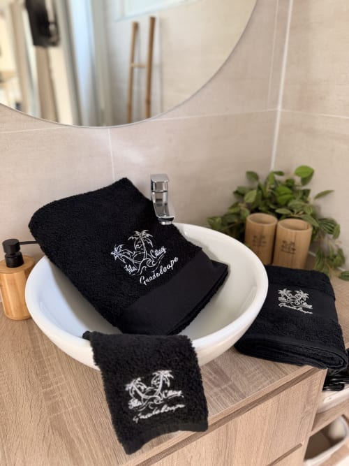 Black embroidered towels displayed in white basin at Filao Cottage, Sainte-Rose Guadeloupe