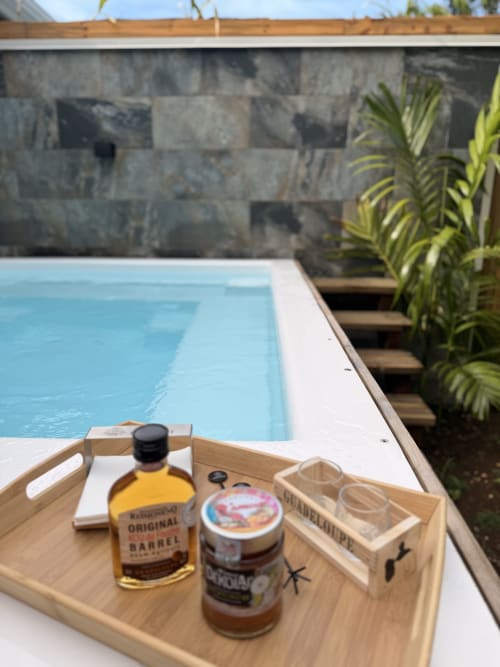 Plateau en bois avec bouteille de rhum et condiments au bord de la piscine, chambre Anse Caraïbe, Filao Cottage, Sainte-Rose, Guadeloupe