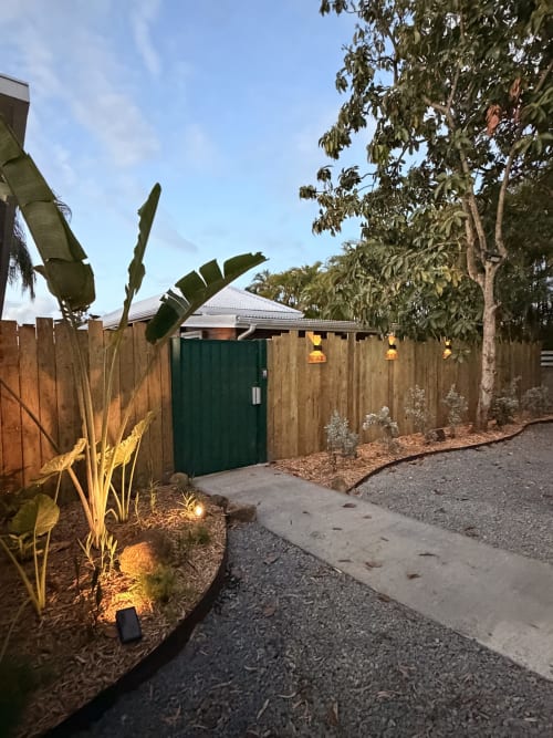Filao Cottage entrance in Sainte-Rose, Guadeloupe, with wooden gate, tropical plants, and lit pathway at dusk