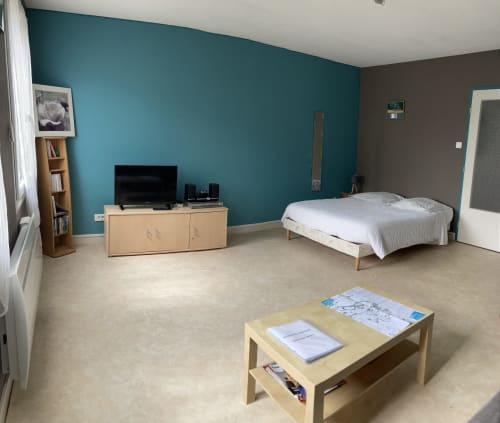 Chambre moderne de l'appartement Chez Mimi à Châtillon-sur-Seine avec mur d'accent turquoise, lit, meuble TV et coin séjour