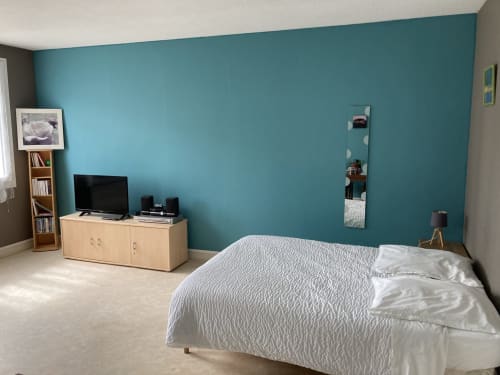 Chambre moderne aux murs turquoise, literie blanche, téléviseur et meubles en bois chez Chez Mimi Meublé Tourisme