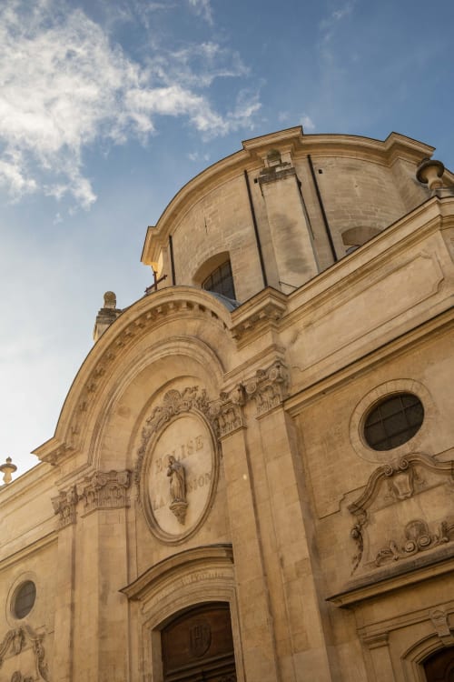 Historic stone chapel facade at Le Prieuré Notre-Dame in Montfrin, France, featuring ornate architectural details and clear