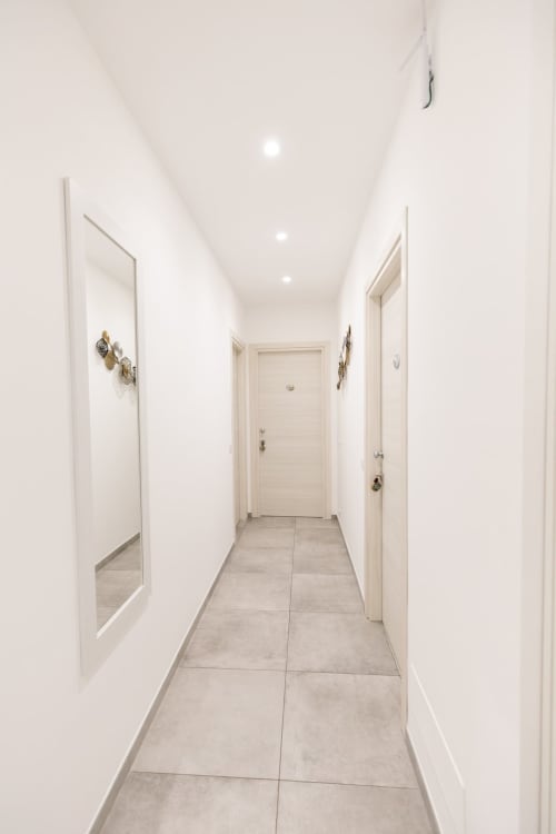 Bright modern hallway at L'Amaranto B&B in Agerola with white walls, recessed lighting, and tiled flooring leading to rooms