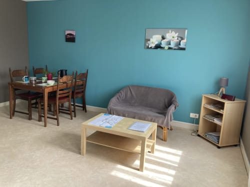 Séjour turquoise lumineux avec table à manger, canapé gris, table basse et rangements dans l'appartement de Châtillon-sur-Seine