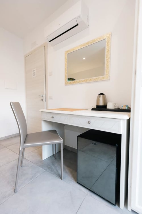 Modern hotel room desk at L'Amaranto B&B in Agerola with chair, mirror, and refrigerator