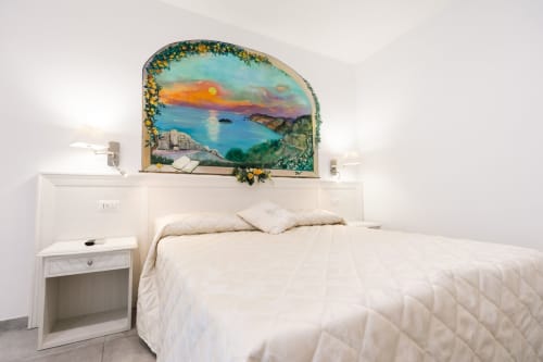 Bright bedroom at L'Amaranto B&B in Agerola with sunset sea view mural above white bed