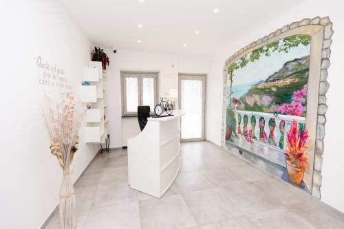 L'Amaranto hotel lobby in Agerola with white reception desk, mural of Amalfi Coast flowers, and modern decor