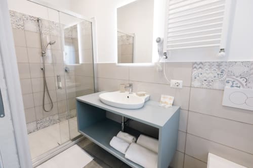 Bagno moderno del B&B L'Amaranto ad Agerola con lavabo, doccia, vanità turchese e asciugamani bianchi
