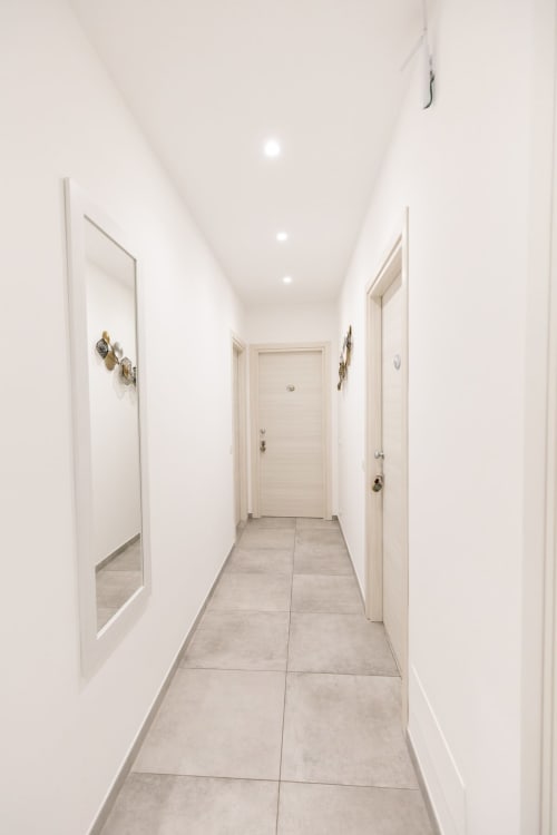 Modern hallway at L'Amaranto B&B in Agerola with white walls, gray tile flooring, and recessed lighting