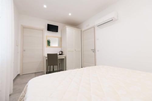 Modern bedroom at L'Amaranto B&B in Agerola with white bed, desk, wardrobe, and TV in Valle delle Feriere room