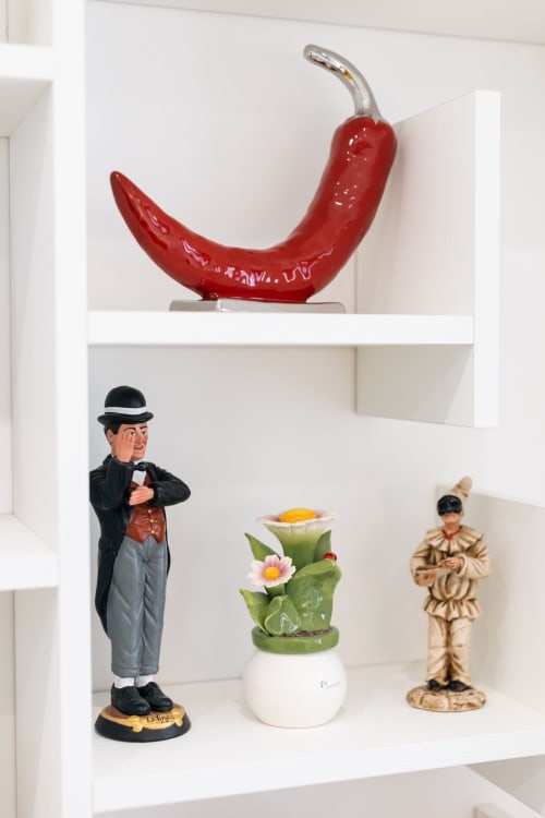 Decorative white shelving with red ceramic chili pepper, vintage figurines and flower pot at L'Amaranto B&B