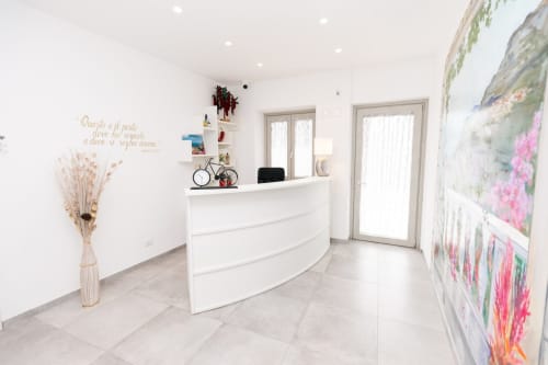 L'Amaranto BnB reception desk in Agerola with modern white counter, decorative flowers and floral artwork