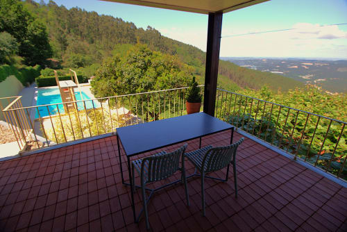 Covered terrace with dining table overlooking pool and mountain valley views at Pera da Serra rural hotel, Lousã Portugal