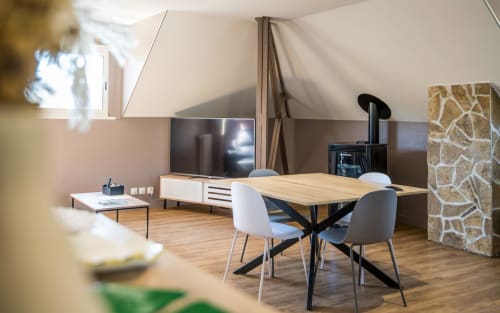 Séjour moderne à Millau avec table en bois, chaises grises, télévision et cheminée en pierre