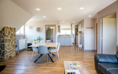Bright open-plan living area in Millau apartment with dining table, modern kitchen, wood flooring, and contemporary