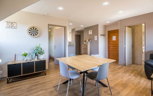 Bright Appt Alba apartment in Millau with wooden dining table, modern chairs, black sideboard, and open-plan living space