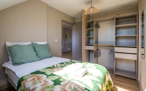 Bright bedroom in Millau apartment with queen bed, green bedding, and built-in wooden wardrobe with mirror