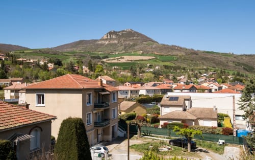 Modern apartment Alba in Millau with city view, terracotta roofed houses, and rocky mountain peak in background