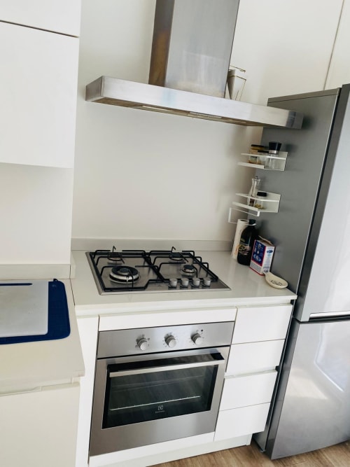 Modern kitchen in Milano Underground apartment with gas cooktop, stainless steel oven, and white cabinetry
